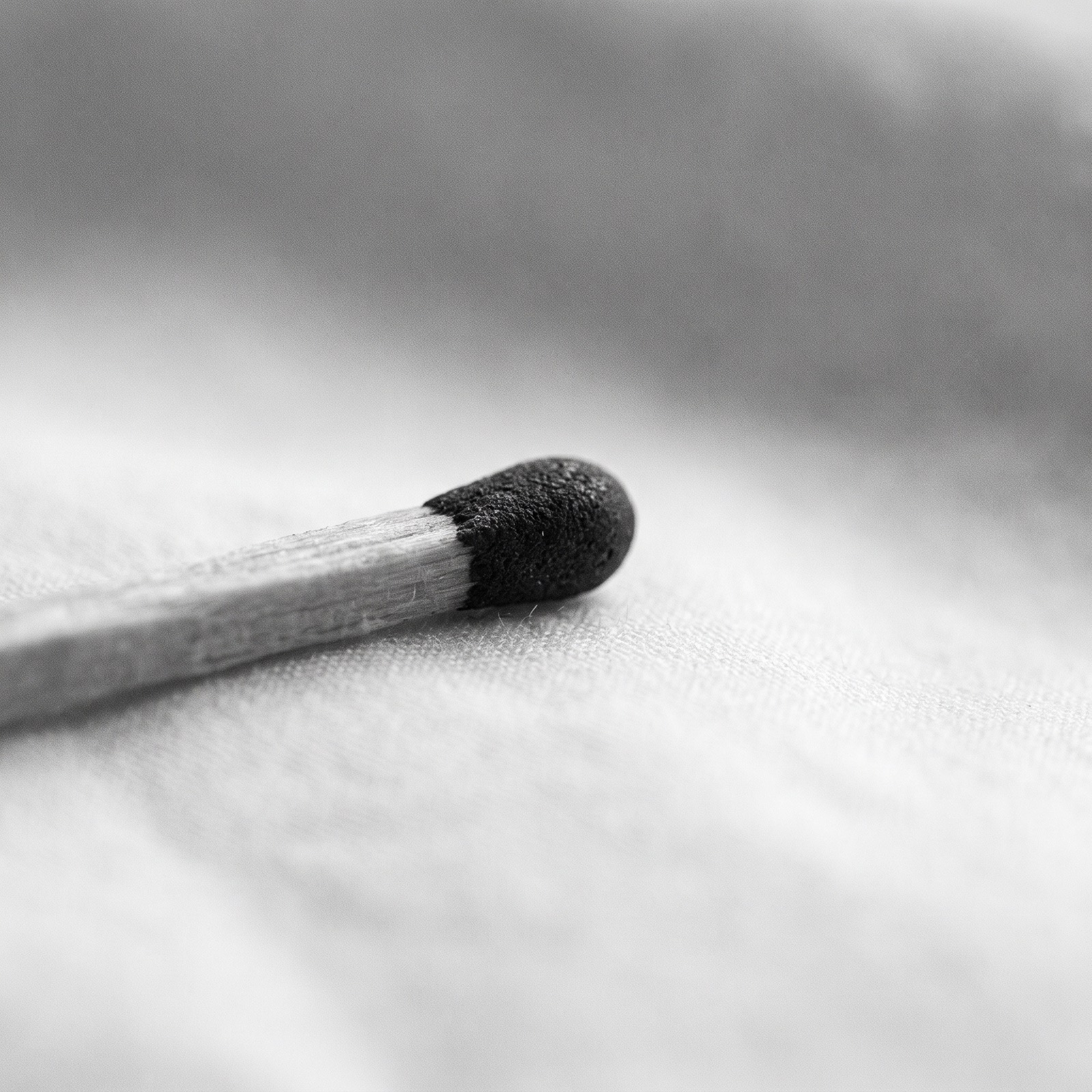 A single unlit match on a pale surface